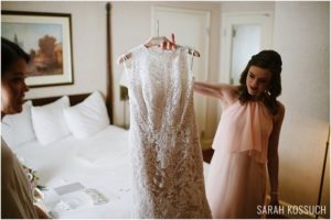 Bridesmaid holds up wedding gown